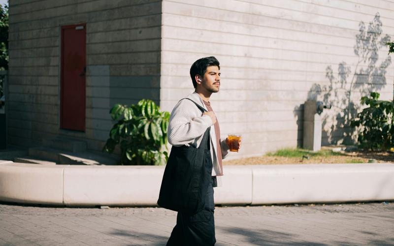 A man walking and carrying a coffee cup.